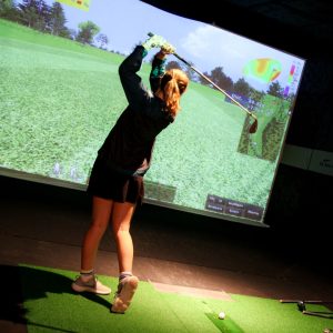 Female swinging in the golf simulator.