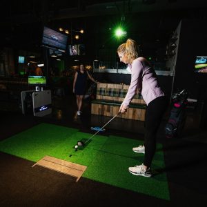 Two girls using the golf simulator.